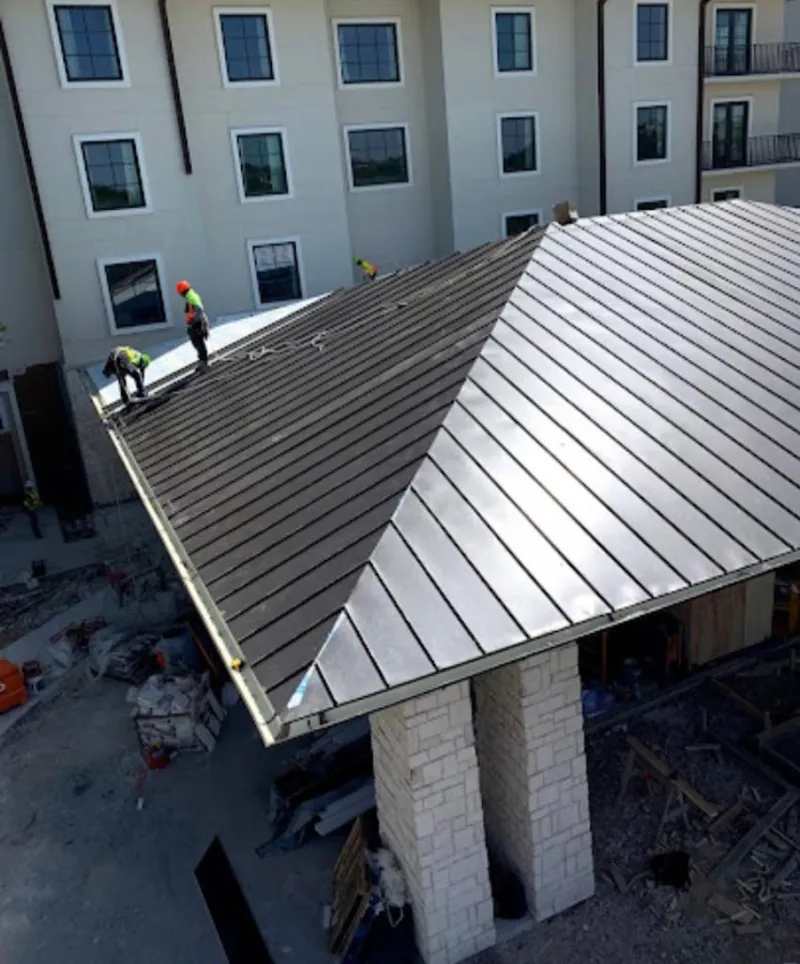 Crew installing standing seam metal roof panels on a commercial project in Forest Park